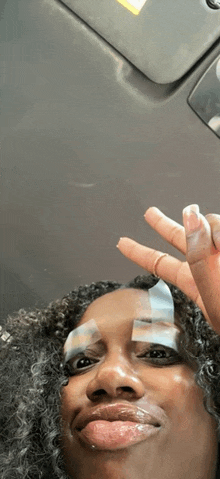 a woman with a bandage on her face is making a peace sign with her fingers .