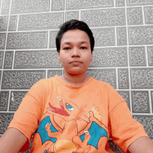 a man wearing an orange shirt with a cartoon dragon on it