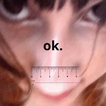 a woman 's nose is measured by a ruler and the word ok is above it