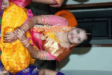 a woman wearing a yellow and pink dress is sitting down