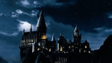 the hogwarts castle is lit up at night with a lightning bolt in the background .