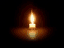 a single lit candle in the dark with a reflection .