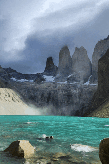 a lake with mountains in the background and a few rocks in the water