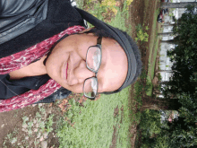 a woman wearing glasses and a scarf is standing in a park