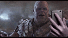 thanos from avengers is taking a selfie with a cell phone .