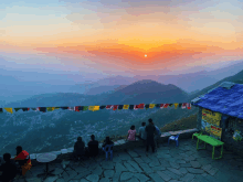 a group of people looking at a sunset over a mountain