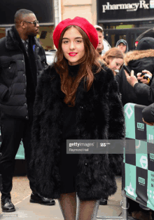 a woman wearing a red hat and a black fur coat