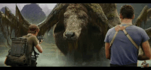 a man holding a gun stands next to a large animal in the water