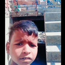 a young boy is making a funny face in front of a staircase .