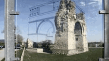 a drawing of a bridge is behind a fence with a ruined building in the background .