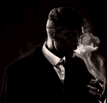 a man in a suit and tie smoking a cigarette