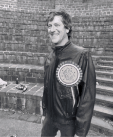 a man in a leather jacket has a rosette that says most best guy