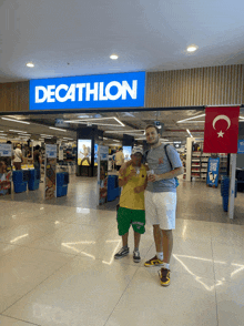 a man and a boy pose in front of a decathlon store