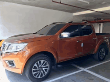 an orange pickup truck is parked in a parking garage