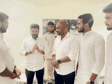 a group of men wearing white shirts stand in a room