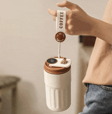 a person is holding a coffee mug with a strap that reads coffee