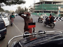 a man with a beard is standing in the middle of a street holding a red and black flag .