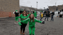 a group of people are dancing in a parking lot with a sign that says ' st. patrick 's day ' on it