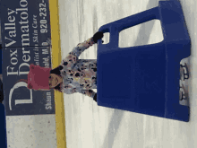 a little girl is ice skating in front of a sign for fox valley dermatolo