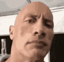 a close up of a bald man 's face with a smirk on his face .