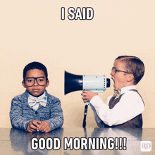 two boys are sitting at a table and one is holding a megaphone with the words i said good morning written on it