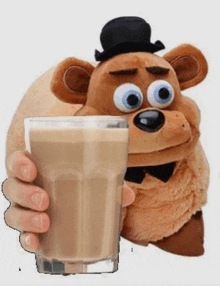 a stuffed teddy bear is holding a glass of chocolate milk