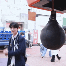 a man in a suit is standing next to a punching bag with a sign that says ' ism ' on it