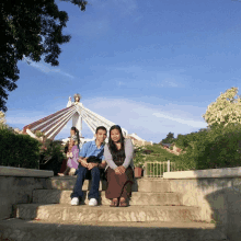 a man and a woman sit on a set of steps in front of a statue