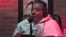 a man wearing headphones is sitting in front of a microphone and talking into it .