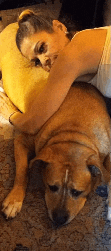 a woman is laying on top of a brown dog on the floor