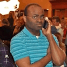 a man wearing glasses and a blue shirt is talking on a cell phone .