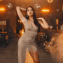 a woman in a silver dress is standing in a room with candles and disco balls