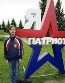 a boy stands in front of a patriotic sign in russian