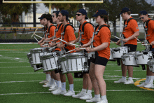 a group of young men and women are playing drums on a field and one of their shirts says " ip "