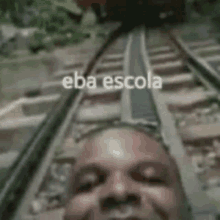 a man is taking a selfie on a train track with a caption that says eba escola .