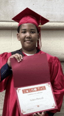 a boy in a graduation cap and gown is holding a certificate that says aiden powell