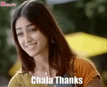 a woman is smiling and saying , ' chala thanks ' while standing in front of a yellow umbrella .