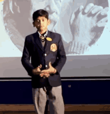 a young boy in a suit and tie is standing in front of a projector screen