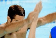 a man is doing a dab in a swimming pool while a woman watches .