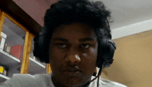 a man wearing headphones and a microphone looks at the camera with a serious look on his face