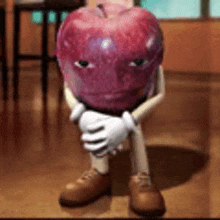 a cartoon apple with arms and legs is sitting on the floor with his hands folded .