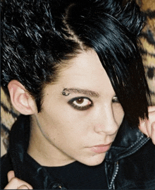 a man with a piercing in his eyebrow is wearing a black jacket