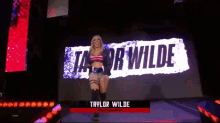 a female wrestler named taylor wilde is walking on a stage