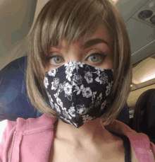 a woman wearing a black and white floral face mask on an airplane