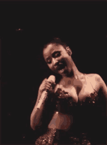 a woman is singing into a microphone on a stage with her breast exposed .