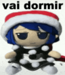 a stuffed toy with blue hair and a santa hat is sitting on a white surface .