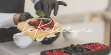 a person wearing black gloves is holding a waffle with raspberries and blackberries on top