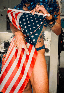 a man in an american flag outfit holds an american flag in his hand