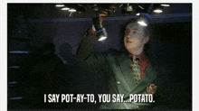 a man in a suit and tie is holding a flashlight and saying " i say pot-ay-to you say potato "