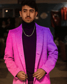 a man wearing a pink jacket and purple turtleneck